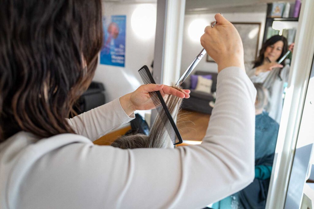 Mitarbeiterin schneidet die Haarspitzen einer Kundin im Friseurladen Bamberg