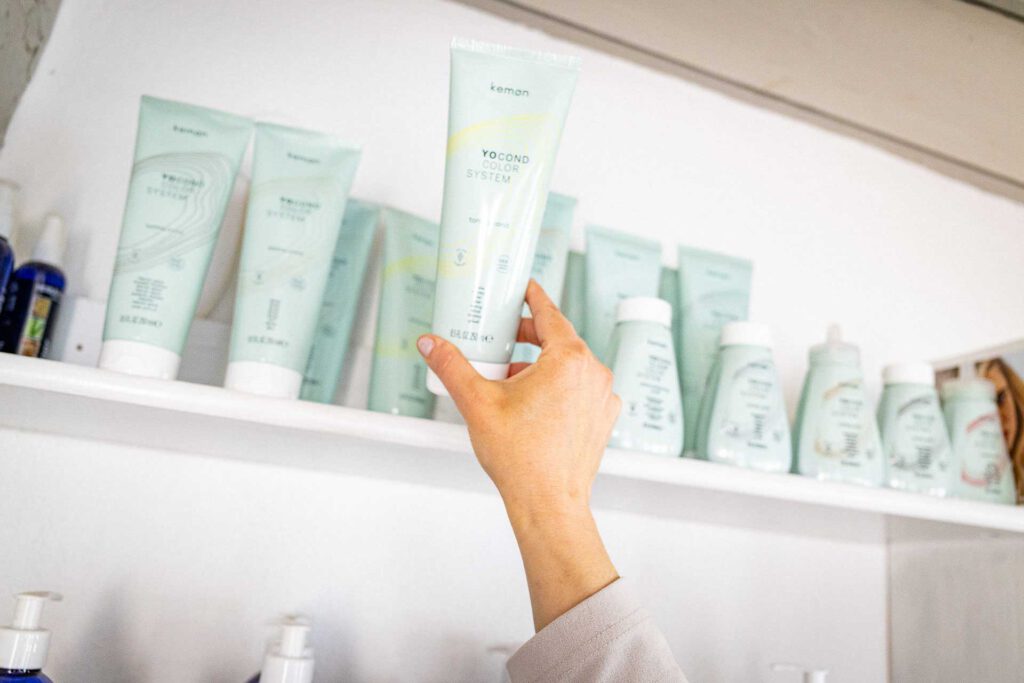 Mitarbeiterin wählt ein Haarpflegeprodukt passend zu den individuellen Haarbedürfnissen aus
